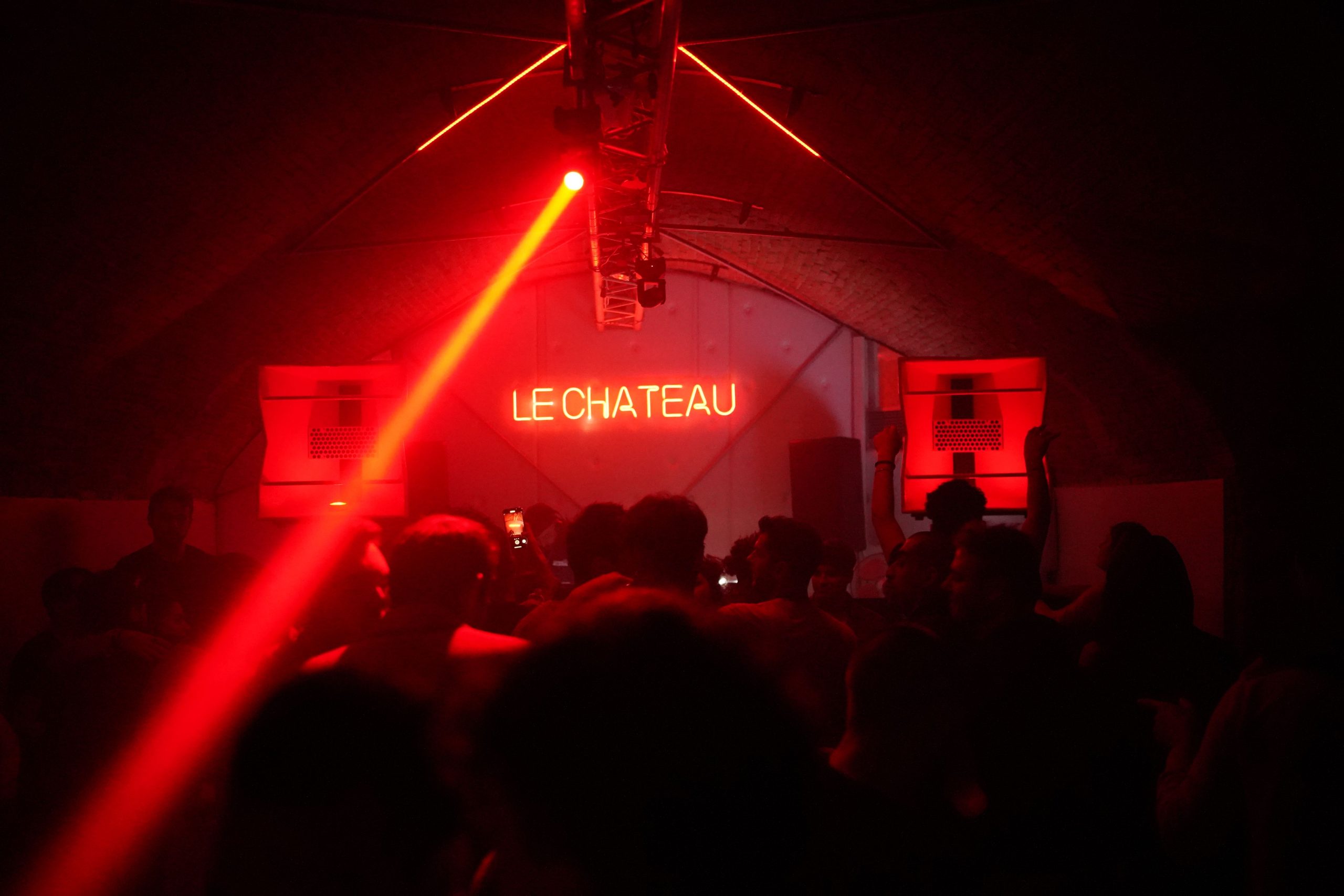 A lively crowd enjoys the nightlife under red neon lights at Le Chateau nightclub.