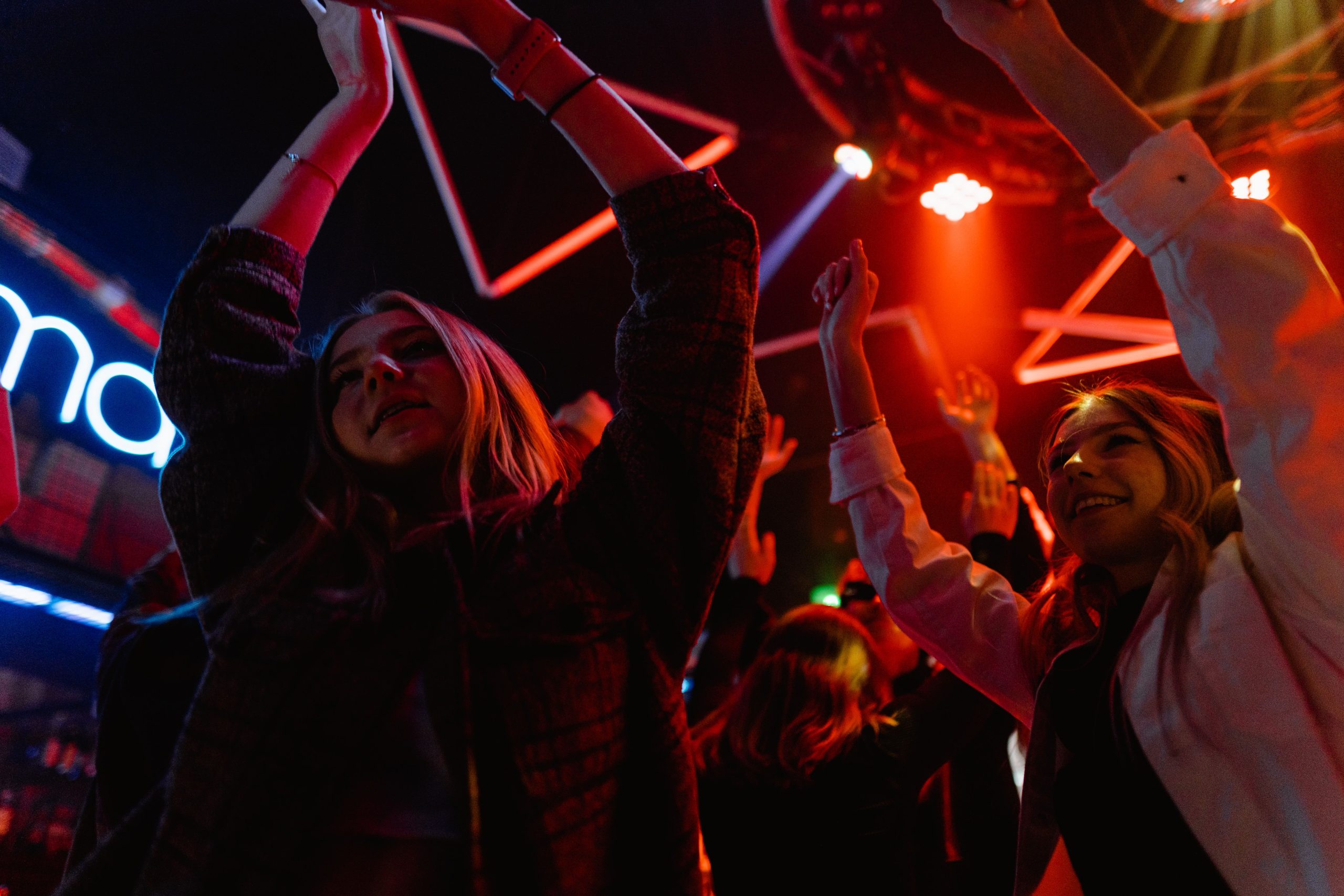 Exciting nightclub scene with people dancing and vibrant neon lights.